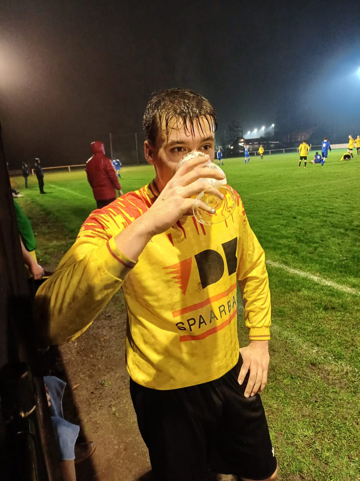 Speler drinkt een pint in de regen langs de lijn